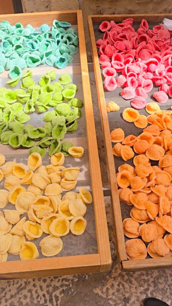 Trays of colorful fresh handmade orecchiette pasta drying in Bari, Puglia.