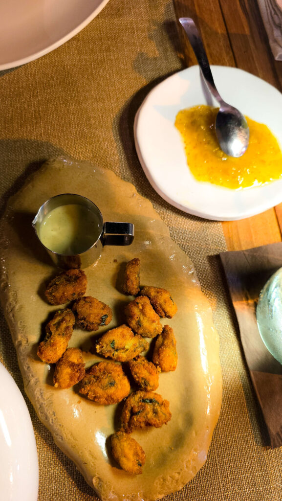 Plate of fried seafood bites with a side of sauce and a spoon on a table in Ostuni.