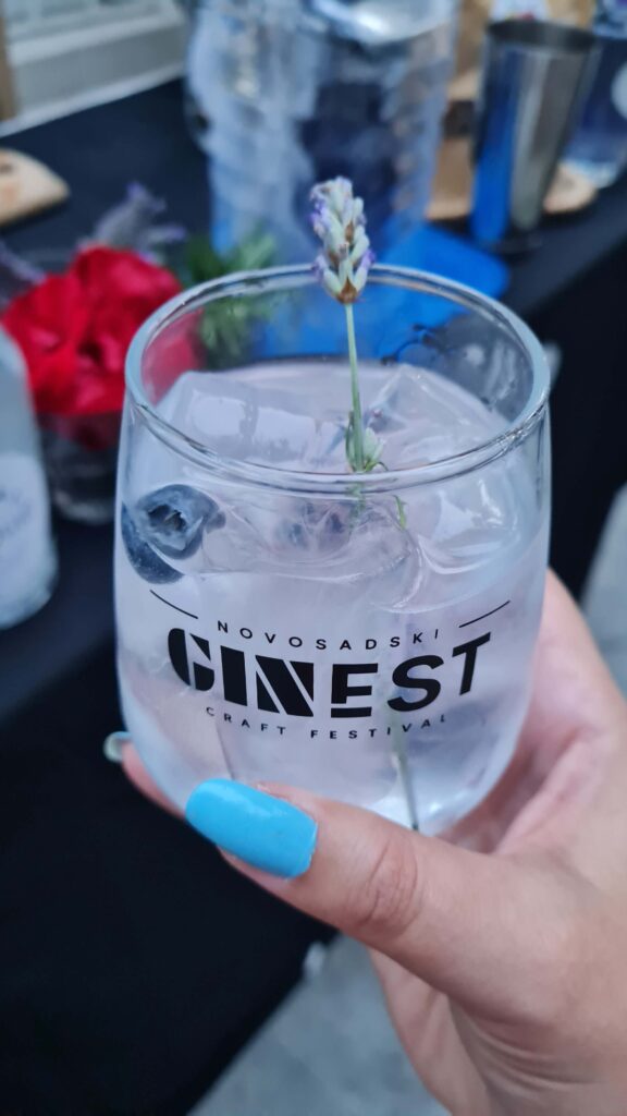 Close-up of a gin and tonic cocktail garnished with lavender and blueberries in a GinFest glass