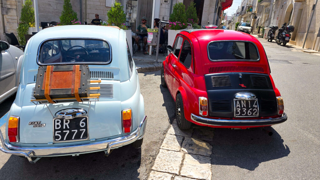 Two vintage Fiat 500 cars parked on a charming street, ready for Puglia road trip. Exploring Puglia by car is the best way to see it.