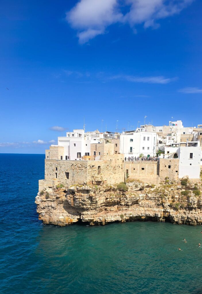 White buildings of Polignano a Mare perched on limestone cliffs overlooking the Adriatic Sea.