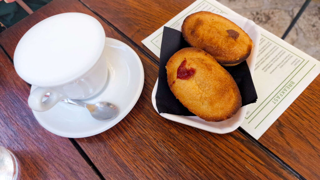 Two traditional Puglian pasticciotto pastries with a coffee on a wooden table.