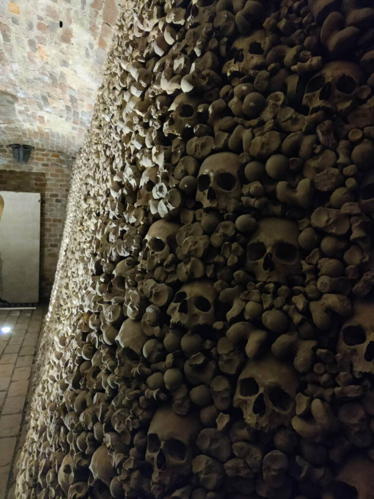Interior of an ossuary in Brno, showing walls lined with human skulls and bones.