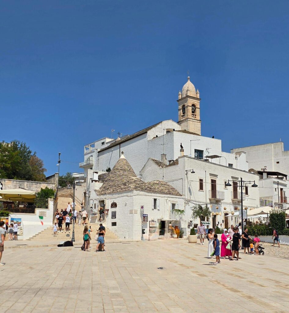 Alberobello guide to the main square with a trulli house and church.
