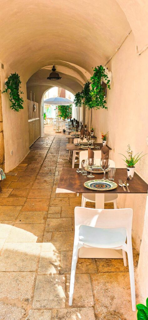 An outdoor restaurant in Matina Franca with tables set up in an archway.