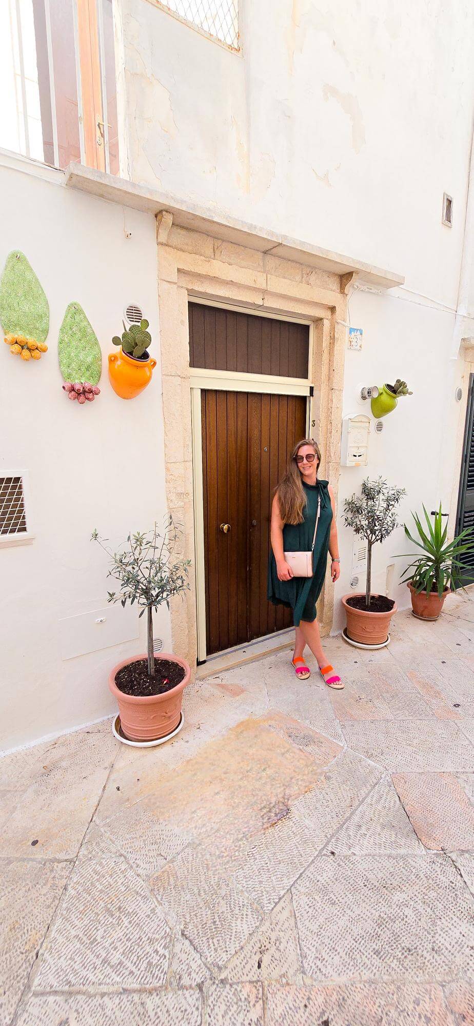 A woman posing in front of a door on a Locorotondo street.