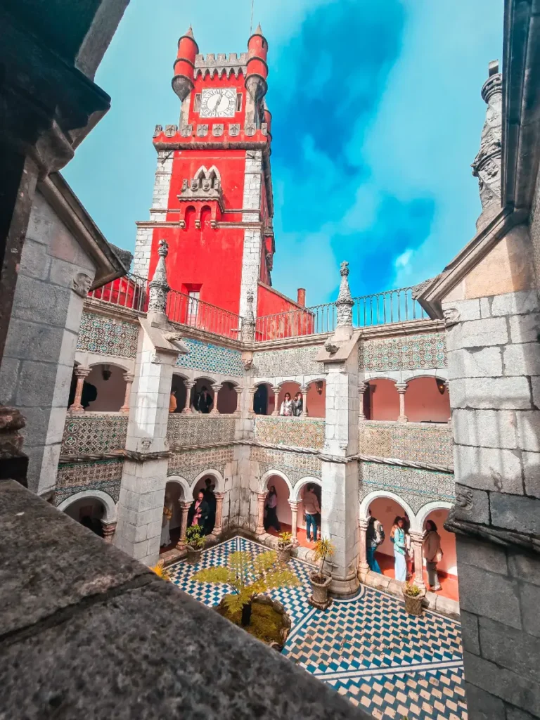 Colorful courtyard and red clock tower of Pena Palace in Sintra, Portugal, must do day trip of the Lisbon travel guide.