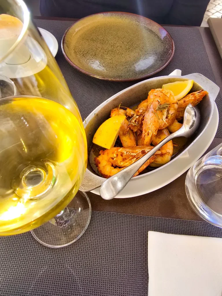 Close-up of grilled shrimp with lemon and a glass of white wine in Cascais restaurant