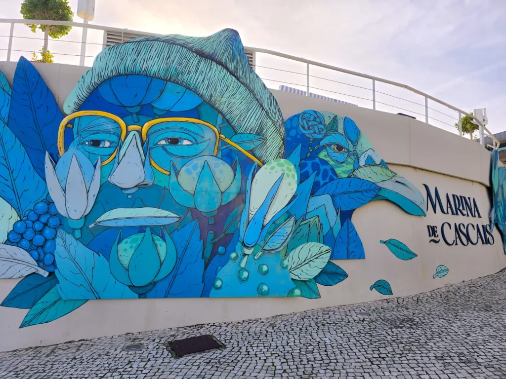 Blue mural at Marina de Cascais featuring artistic sea-inspired faces and flowers