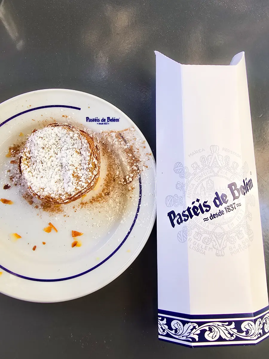 Traditional Pastel de Belém pastry served on a plate with powdered sugar and cinnamon in Lisbon, Portugal