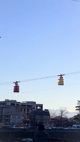 The historic yellow and red cable car cabins traveling over the Rioni River, a unique viewpoint mentioned in our Kutaisi travel guide.