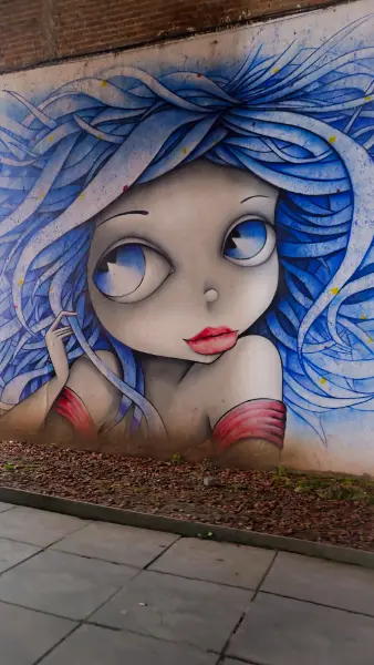Vibrant blue-haired girl mural in Kutaisi, showcasing the city's modern creative side.