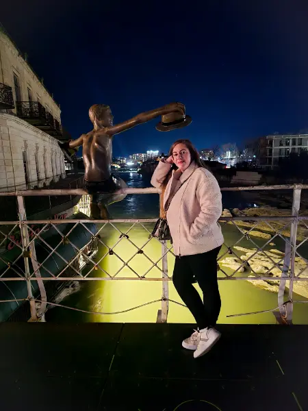 The bronze statue of a boy holding two hats on the White Bridge at night, a famous photo spot in any Kutaisi travel guide.