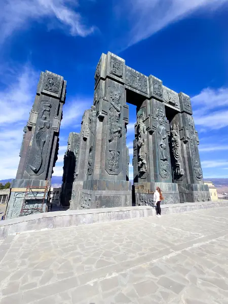 Massive black stone pillars of the Chronicles of Georgia monument under a blue sky.