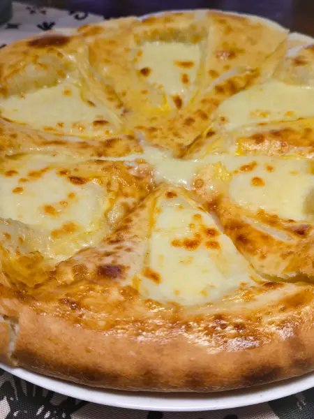 Freshly baked Megrelian khachapuri topped with extra cheese, a must-try dish for visitors using a Kutaisi travel guide.